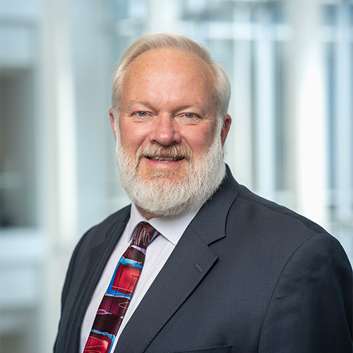 Ken Ball wears a colorful tie and dark gray suit