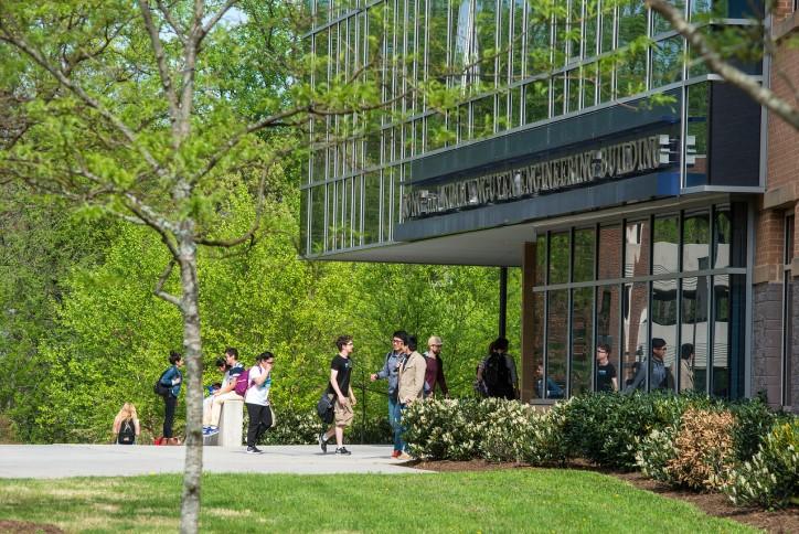 Students standing outside of the engineering building, coming in and out. 