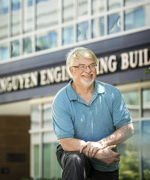 Jeff Offutt standing in front of the the engineering  building on a sunny day.